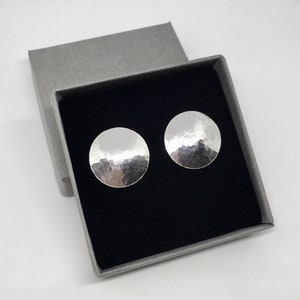 May include: A pair of silver hammered disc earrings in a gray gift box with a black interior.