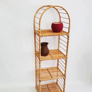 May include: A four-tiered, arched, wicker shelf unit with a red pot on the top shelf and a brown clay pot on the second shelf.