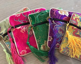 May include: Five small zippered pouches with tassels. The pouches are made of colorful brocade fabric with floral and dragon designs. The pouches are lined with a cream-colored fabric.