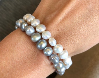 May include: A bracelet made of two strands of pearls. The top strand is made of gray pearls and the bottom strand is made of white pearls.