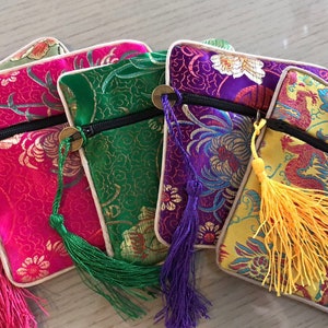 May include: Five small zippered pouches with tassels. The pouches are made of a colorful brocade fabric with floral and dragon designs. The pouches are lined with a cream-colored fabric.