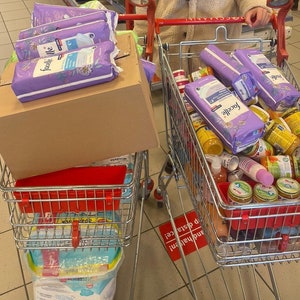 May include: Two shopping carts filled with various items. One cart contains a stack of purple and white boxes with the word "Facelle" printed on them. The other cart contains a variety of jars and bottles, including baby food jars and a few bottles of lotion.