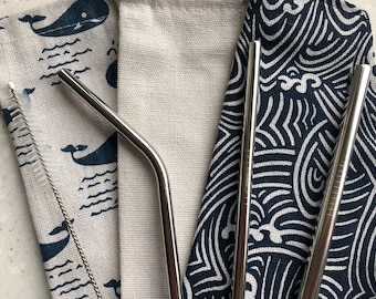 May include: A reusable stainless steel straw set with a cleaning brush and carrying cases. The set includes straight and bent straws. The cases feature whale and wave patterns in navy blue and white.