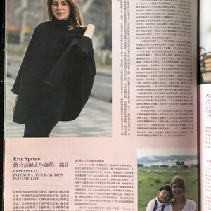 May include: A woman in a black cape stands in front of a white background. The text "Erin Sprute: Integrate Charities into My Life" is printed in black on a white background. The text "Erin Sprute" is in a larger font size than the rest of the text.