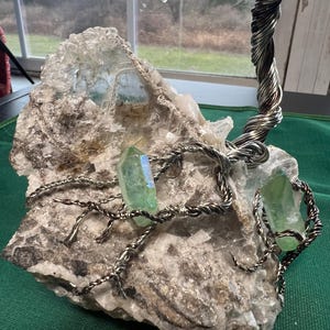 May include: A wire-wrapped tree sculpture with green crystals and a large, white, crystal base.