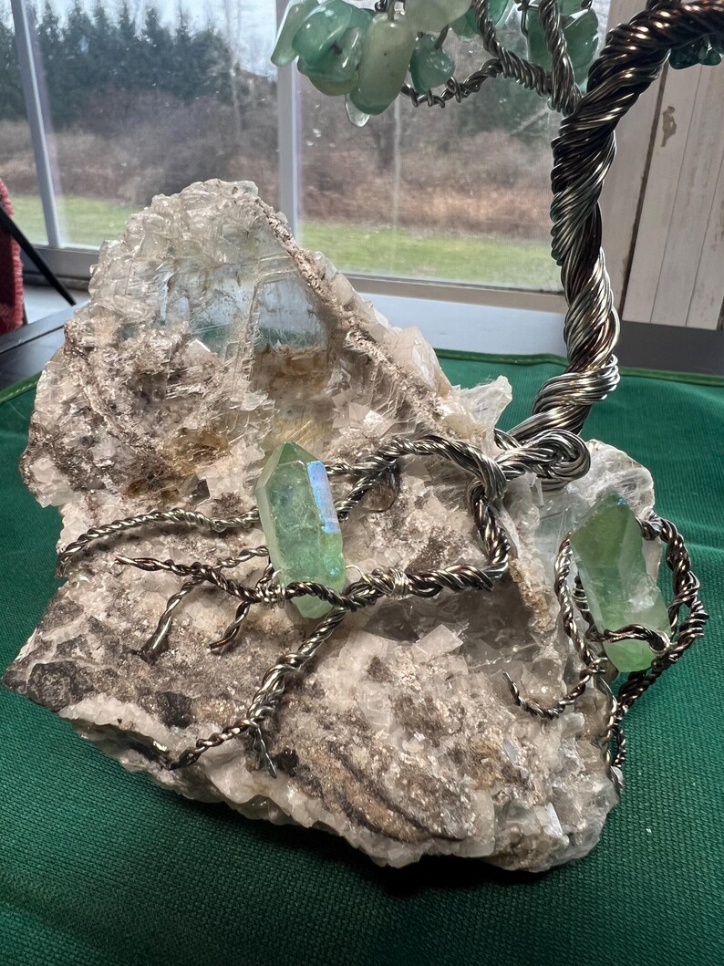 May include: A wire-wrapped tree sculpture with green crystals and a large, white, crystal base.