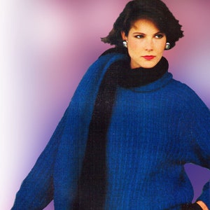 May include: A woman wearing a blue sweater with a black scarf and gray pants. She is holding a luggage cart.