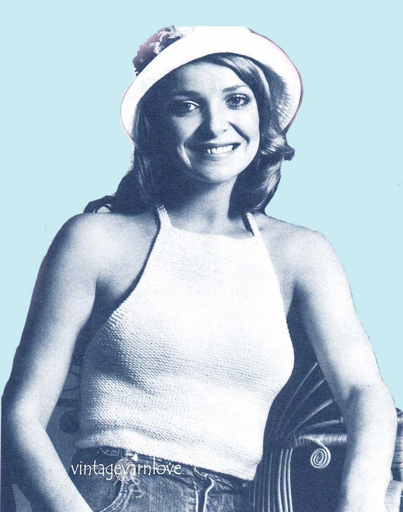May include: A white crochet halter top with a crocheted white hat with a flower accent. The model is wearing blue jeans.