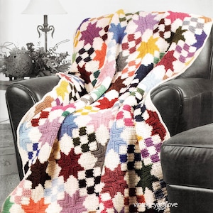 May include: A colourful crocheted afghan with a patchwork design featuring stars and squares. The afghan is draped over a leather armchair and footstool.