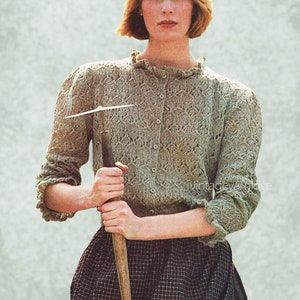 May include: A pale green, open-stitch cardigan with a frilled collar and cuffs. The cardigan is buttoned and worn with a plaid skirt. A person is holding a tool with a wooden handle. The image has a vintage aesthetic.