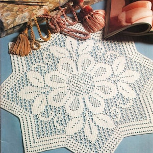 May include: White crocheted doily with a starburst design. The doily is made with a delicate, openwork pattern and has a scalloped edge.