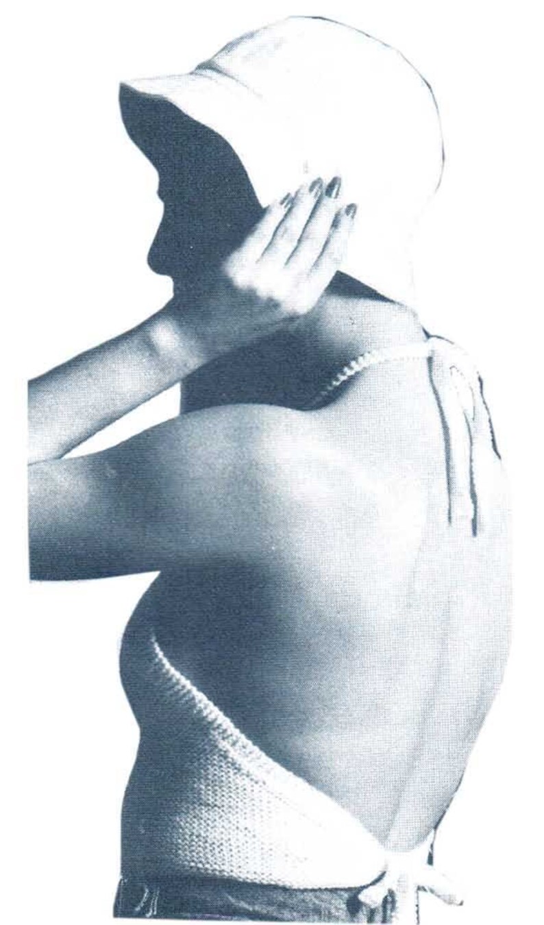 May include: A white crocheted halter top with a tie closure at the back. The top is worn with a white sun hat and blue jeans.