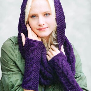 May include: A woman wearing a purple hooded scarf and matching fingerless gloves. The scarf and gloves are knitted with a cable pattern.