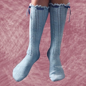 Può includere: Un paio di calze blu chiaro che arrivano al ginocchio con un delicato motivo a pizzo e lacci di nastro blu. Le calze hanno un bordo a pois bianchi in alto.