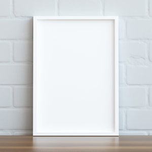 May include: A white picture frame with a white mat, sitting on a wooden table in front of a white brick wall.