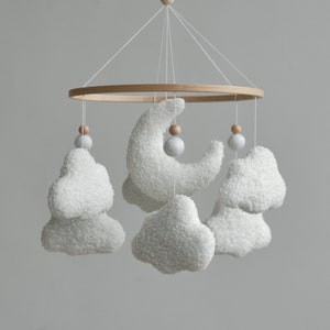 Handcrafted baby mobile made from bouclé, adorned with fluffy clouds, a crescent moon, and charming wooden balls. This baby crib mobile is a perfect neutral nursery decor.