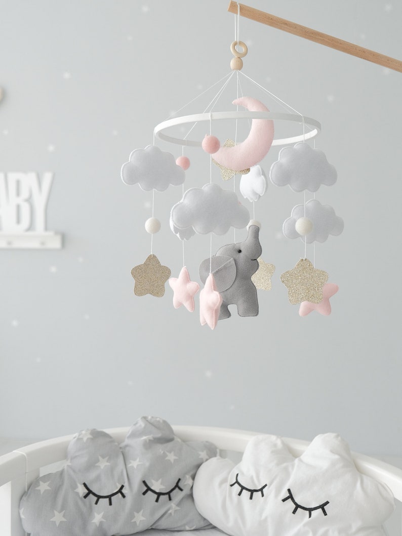 Introducing our Elephant Baby Crib Mobile, a perfect addition to your elephant nursery decor, showcasing delightful pink accents and golden glitter stars for a whimsical and enchanting ambiance.