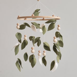 Handcrafted nursery mobile featuring rustic wooden balls and olive felt leaf, designed to complement a natural nursery decor with its earthy tones.