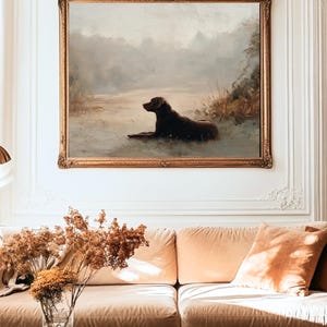K&ouml;nnte beinhalten: Antikes &Ouml;lgem&auml;lde eines Hundes, der sich an einem Gew&auml;sser ausruht, in einem goldenen, verzierten Rahmen. Das Kunstwerk zeigt einen braunen Hund in einer ruhigen Landschaft mit ged&auml;mpften Farben. Das Gem&auml;lde wird &uuml;ber einem pfirsichfarbenen Sofa ausgestellt.