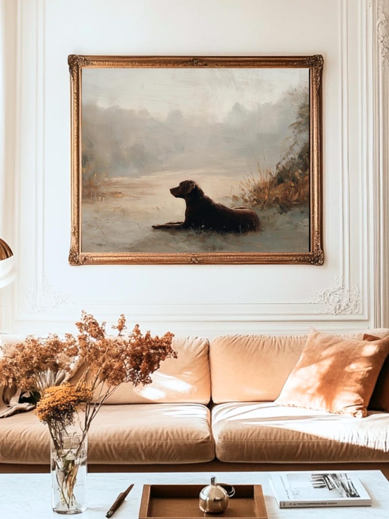 K&ouml;nnte beinhalten: Antikes &Ouml;lgem&auml;lde eines Hundes, der sich an einem Gew&auml;sser ausruht, in einem goldenen, verzierten Rahmen. Das Kunstwerk zeigt einen braunen Hund in einer ruhigen Landschaft mit ged&auml;mpften Farben. Das Gem&auml;lde wird &uuml;ber einem pfirsichfarbenen Sofa ausgestellt.
