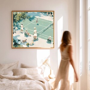 May include: A framed art print depicts a tennis match scene in a vintage style. The artwork features players in white attire, spectators, and dogs on a green court. The frame is gold, and the overall color palette is soft and muted.