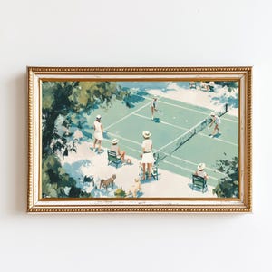 May include: A framed print depicts a tennis scene with players in white attire on a green court. Spectators in hats and dogs are present. The artwork is framed in a gold-colored ornate frame, evoking a vintage aesthetic.