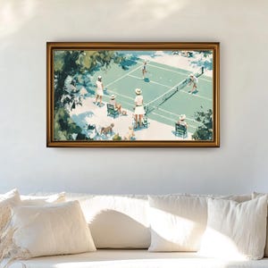 May include: A framed art print depicting a tennis match scene. The artwork features players in white attire on a green court, surrounded by trees and spectators. The frame is gold-toned, and the overall aesthetic is vintage.