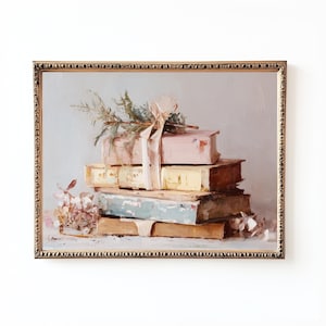 May include: An antique-style framed painting depicts a stack of old books in shades of beige, blue, and pink. A pink ribbon and sprigs of greenery adorn the top book. The artwork has a soft, muted color palette and a vintage aesthetic.