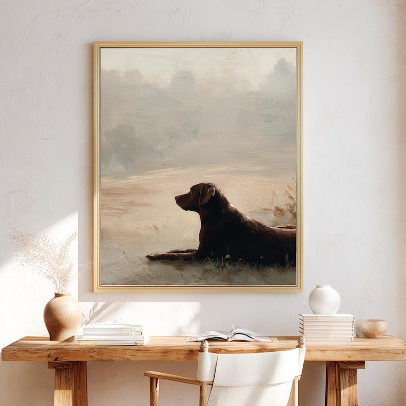 K&ouml;nnte beinhalten: Ein gerahmter Druck mit einem braunen Hund, der in einem Feld liegt. Das Kunstwerk hat eine Vintage-&Auml;sthetik mit weichen, ged&auml;mpften Farben in Braun, Beige und Grau. Der Hund ist der Mittelpunkt, vor einem verschwommenen, atmosph&auml;rischen Hintergrund.