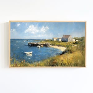 Puede incluir: Pintura al óleo de una escena costera con un muelle, botes y edificios. La obra de arte presenta un mar azul, una playa de arena y un cielo azul brillante con nubes blancas. La pintura está enmarcada en un marco de madera de color claro.