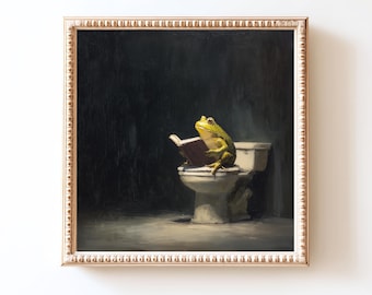May include: A framed artwork depicts a green frog sitting on a toilet, engrossed in reading a book. The frog is illuminated against a dark background, creating a humorous and surreal scene. The frame is gold.
