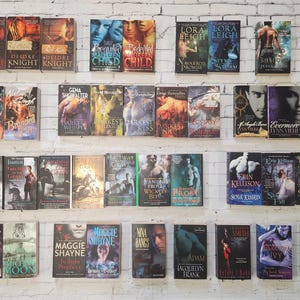 May include: A shelf filled with paperback books, mostly romance novels. The books are arranged in rows and are all different colors. Some of the titles include "Branded", "Darkest Kiss", "Evermore", "Soul Kissed", "Shadow Bound", "Dark Prince", and "Shadow Moon".