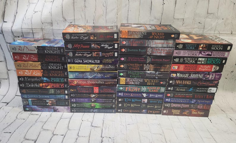 May include: A stack of paperback books with various titles and authors. The books are arranged in a vertical stack, with the spines facing outward. The books are all different colors and have different designs on their covers.