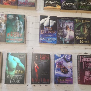 May include: A shelf filled with paperback books, mostly romance novels. The books have titles like "Wicked Bite", "Soul Kissed", "Shadow Fall", "Fire Kissed", "Dark Prince", and "My Lord Vampire".