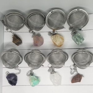 May include: Ten silver tea infusers with chains and various colored crystals attached. The crystals are amethyst, rose quartz, citrine, aventurine, amethyst, amazonite, clear quartz, and red jasper.