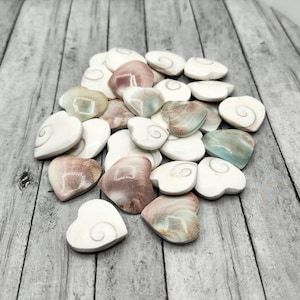 May include: A pile of heart-shaped polished stones with a swirling pattern. The stones are various shades of white, brown, and green.