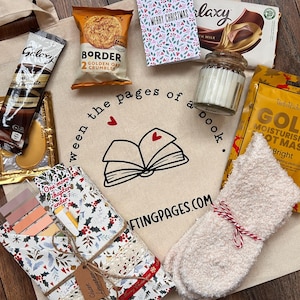 May include: A beige tote bag filled with various items, including a chocolate bar, cookies, a candle, a foot mask, and a pair of fuzzy socks tied with red and white twine. The bag has the text "ween the pages of a book" and "craftingpages.com".
