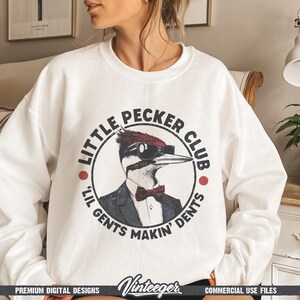 May include: White sweatshirt with a circular graphic featuring a woodpecker wearing sunglasses, a suit, and a bow tie. The text reads "Little Pecker Club" and "Lil Gents Makin' Dents". The sweatshirt has a crew neck.
