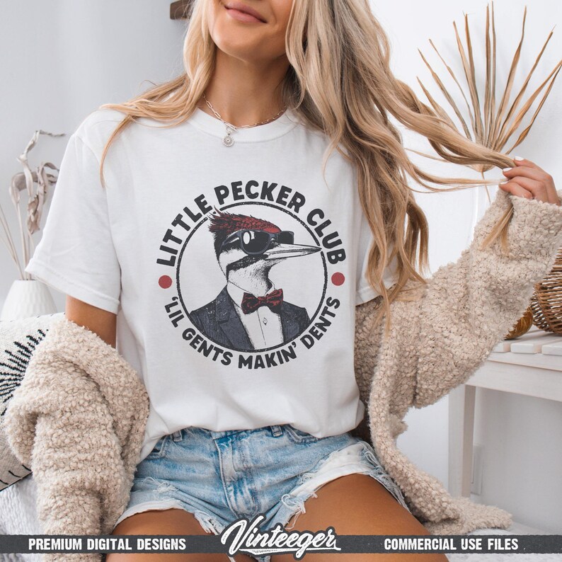 May include: White t-shirt featuring a circular graphic with a cartoon woodpecker wearing sunglasses, a bow tie, and a suit. The text reads "Little Pecker Club" and "Lil Gents Makin' Dents". The shirt has short sleeves.