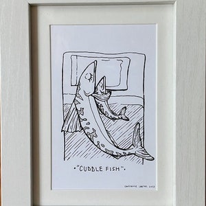 May include: A black and white line drawing of two fish cuddling in a bed. The caption reads "Cuddle Fish."