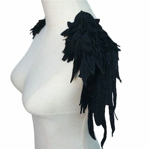 May include: Black lace shoulder embellishments with a feather-like design. The embellishments are made of a soft, delicate fabric and are perfect for adding a touch of elegance to any outfit.