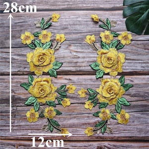 May include: Two yellow embroidered floral appliques with green leaves and stems. The appliques are 12 cm wide and 28 cm tall.