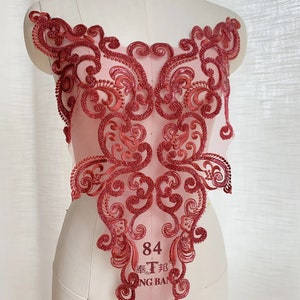 May include: Red lace applique with a floral design. The applique is on a pink mesh background. The applique is about 10 inches tall and 8 inches wide.