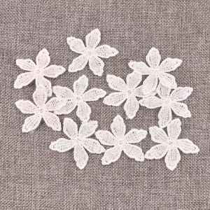 May include: A collection of eight white lace flower appliques, each featuring five petals with a detailed embroidered mesh texture. These small, delicate floral motifs are arranged in a loose cluster, showcasing intricate threadwork and scalloped edges.