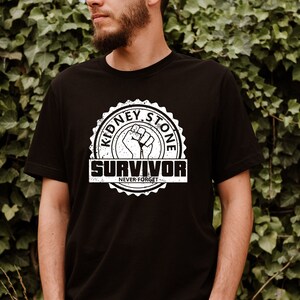 May include: A black t-shirt with a white distressed graphic of a fist and the text "Kidney Stone Survivor Never Forget".