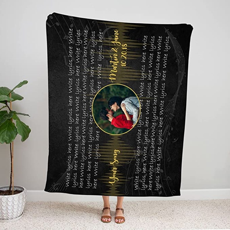 May include: Black and gold personalized blanket with a couple's photo and the text "Your Song" and "Martin & Jane 10.20.18". The blanket is decorated with musical notes.