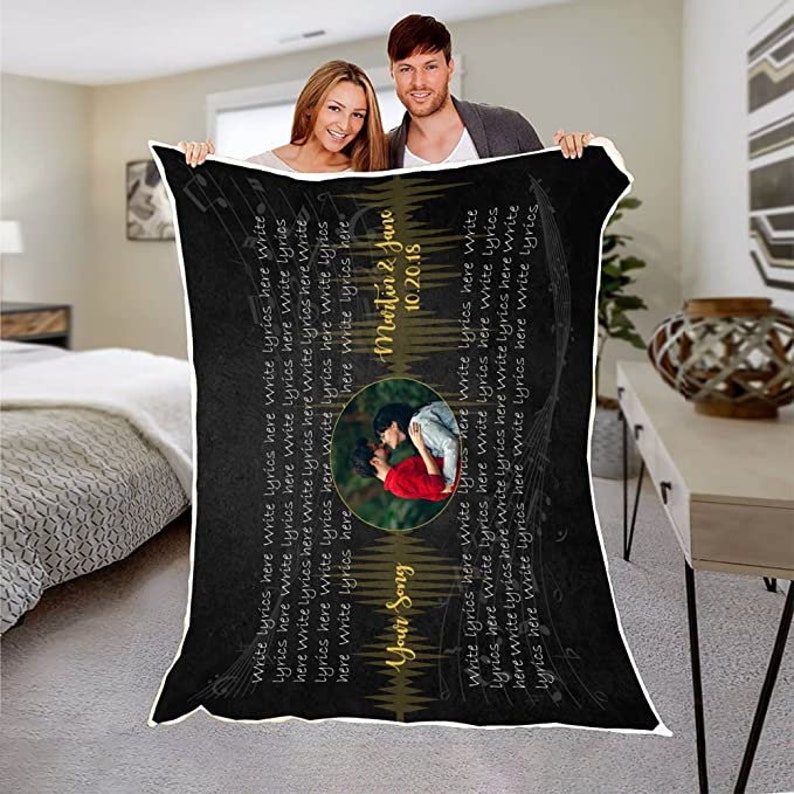 May include: Black and white personalized blanket with a photo of a couple and the text "Your Song", "Martin & Jane", and "10.20.18". The blanket has a musical note design and the text "Write lyrics here" repeated throughout.