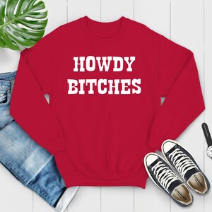 May include: Red sweatshirt with white text that reads "HOWDY BITCHES".