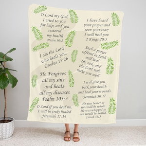 May include: A beige throw blanket with green leaf designs and inspirational bible verses printed in black. The verses include "O Lord my God, I cried to you for help, and you restored my health. Psalm 30:2" and "I am the Lord who heals you. Exodus 15:26".