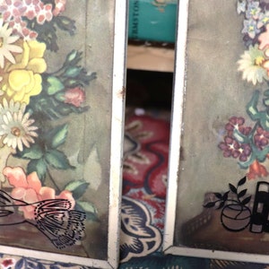 May include: Two framed floral prints with a vintage aesthetic. The prints feature bouquets of flowers in vases, with one print featuring a bird and the other featuring a vase with a textured surface.